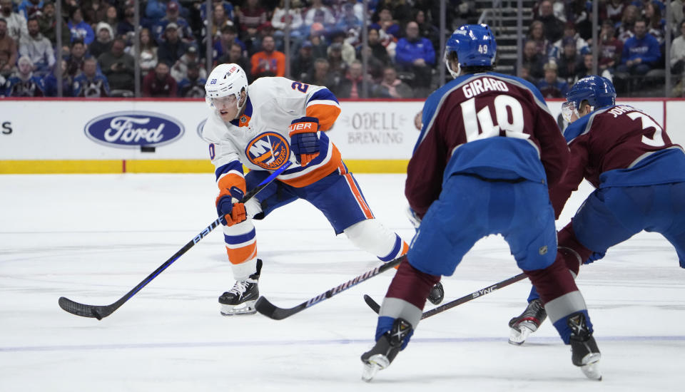 New York Islanders right wing Hudson Fasching, left, looks to pass the puck as Colorado Avalanche defensemen Samuel Girard, center, and Jack Johnson cover in the second period of an NHL hockey game Tuesday, Jan. 2, 2024, in Denver. (AP Photo/David Zalubowski)