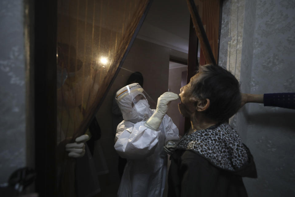 A medical worker takes a swab from a resident for the coronavirus test during home visits in Wuhan the epicenter of China's coronavirus outbreak in central China's Hubei province, Thursday, May 14, 2020. Some residential compounds in Wuhan have begun testing inhabitants for the coronavirus as a program to test everyone in the Chinese city of 11 million people in 10 days got underway. (Chinatopix via AP)