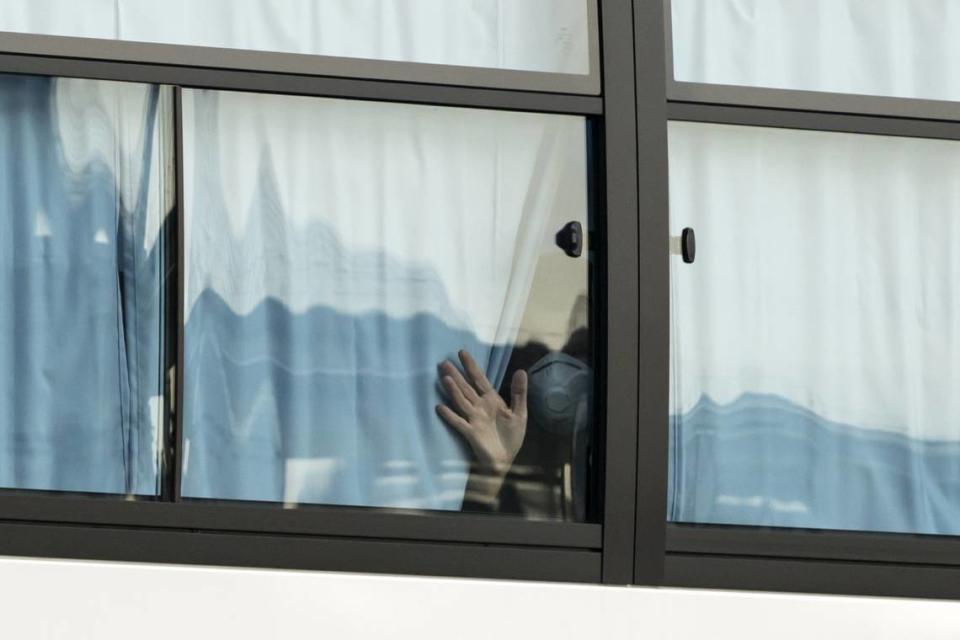 A man waves from a bus carrying passengers who disembarked the quarantined Diamond Princess cruise ship as he leaves the Daikoku Pier on Feb. 19, 2020, in Yokohama, Japan.