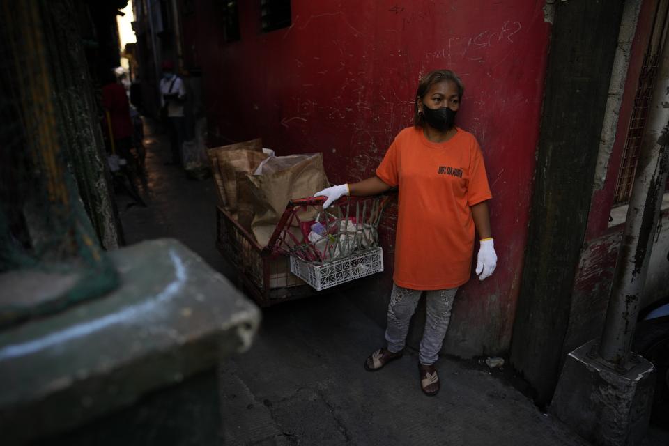 Marilene Capentes waits for segregated garbage beside her cart along the streets of Malabon, Philippines on Monday Feb. 13, 2023. Capentes, who is 47, said the trash used to be all mixed together — and heavy — until a local environmental nonprofit started asking residents to separate it a few years ago. (AP Photo/Aaron Favila)