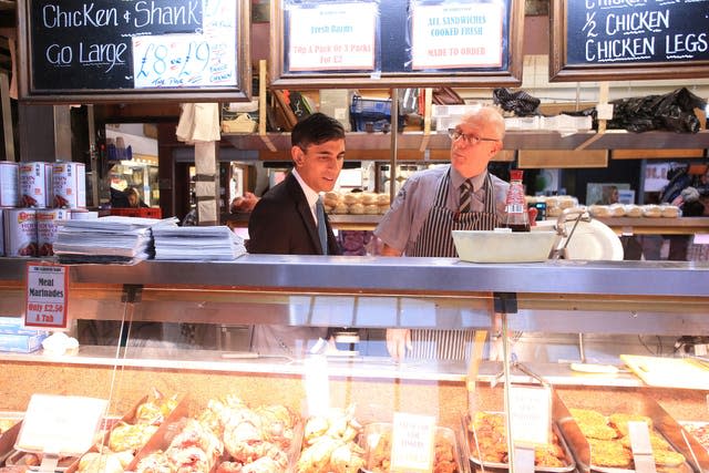 Chancellor Rishi Sunak speaks to a butcher during a visit to Bury market in Lancashire