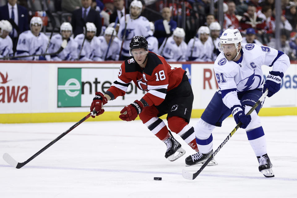 Tampa Bay Lightning center Steven Stamkos (91) skates with the puck past New Jersey Devils left wing Ondrej Palat during the first period of an NHL hockey game Thursday, March 16, 2023, in Newark, N.J. The Lightning won 4-3 in a shootout. (AP Photo/Adam Hunger)