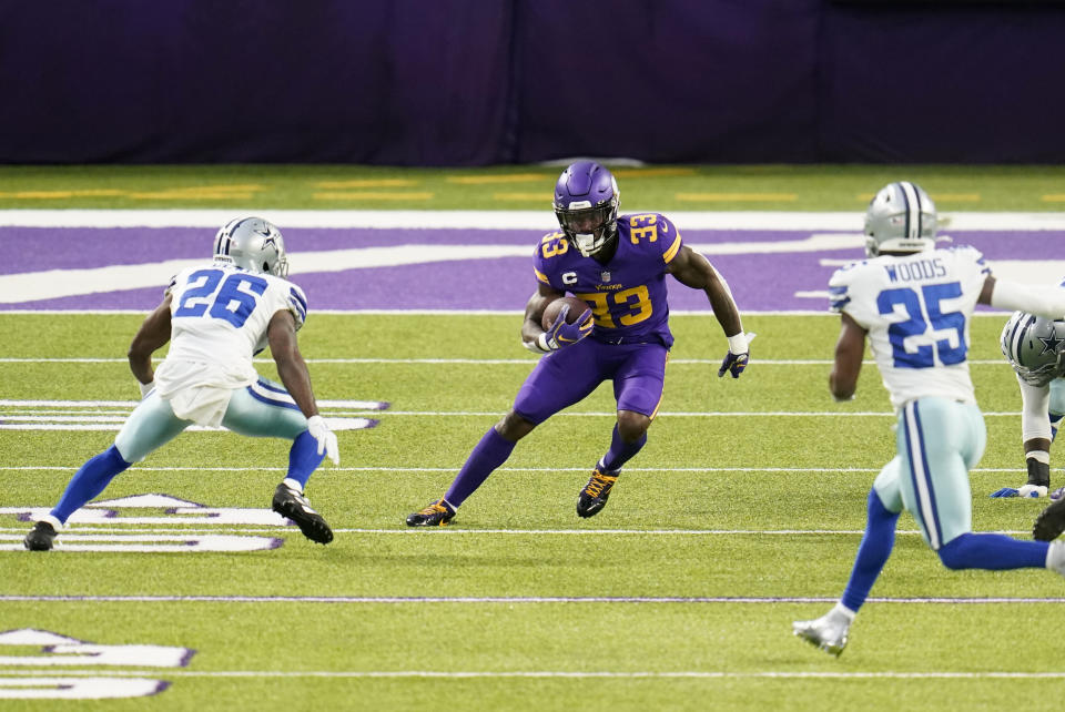 Minnesota Vikings running back Dalvin Cook (33) runs up field between Dallas Cowboys cornerback Jourdan Lewis (26) and safety Xavier Woods (25) during the first half of an NFL football game, Sunday, Nov. 22, 2020, in Minneapolis. (AP Photo/Jim Mone)