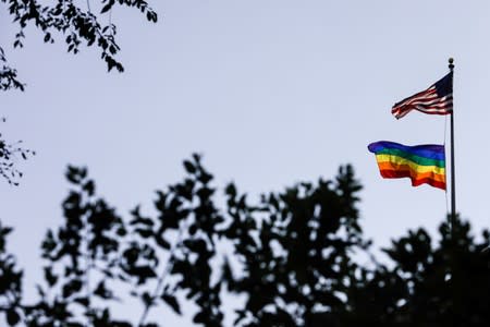 A rainbow pride flag is seen with the U.S. national flag at a building ahead of the 50th anniversary of the Stonewall riot, in New York