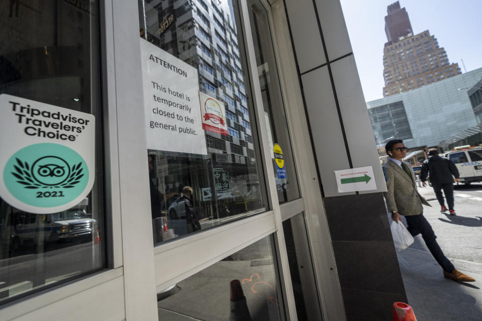 Pedestrians pass the Holiday Inn Manhattan - Financial District hotel on Rector Street, Wednesday, March 29, 2023, in New York. City officials, operating under legal mandates that require New York City to provide shelter to anyone seeking it, have turned to hotels to house busloads of international migrants seeking asylum who have been sent to the city from other states. Around Manhattan and elsewhere in the city, hotels that served tourists just a few years ago have become de facto emergency shelters. The latest is the historic Roosevelt Hotel in midtown Manhattan, which shuttered three years ago, is reopening later this week as a welcome center and shelter for asylum seekers. (AP Photo/John Minchillo)