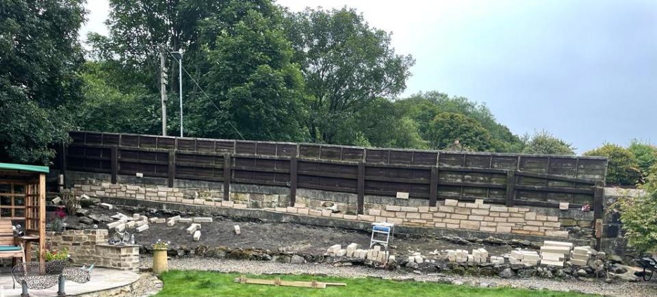 The 4 foot stone wall during construction, seen next to the original 6 foot wooden fence.  (SWNS)