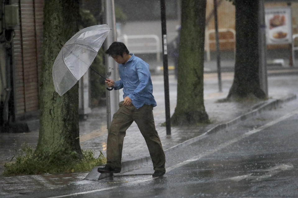 A man crosses the road in Hamamatsu, central Japan, Saturday, Oct. 12, 2019. A heavy downpour and strong winds pounded Tokyo and surrounding areas on Saturday as a powerful typhoon forecast as the worst in six decades approached landfall, with streets and train stations deserted and shops shuttered. (AP Photo/Christophe Ena)