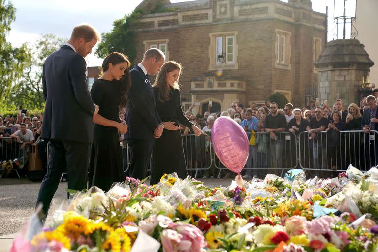 El príncipe británico Harry, duque de Sussex, su esposa Meghan, duquesa de Sussex , el príncipe británico Guillermo, príncipe de Gales y su esposa Kate, princesa de Gales, observan las ofrendas florales depositadas por el público en el paseo largo del castillo de Windsor el 10 de septiembre de 2022 antes de reunirse con los simpatizantes.