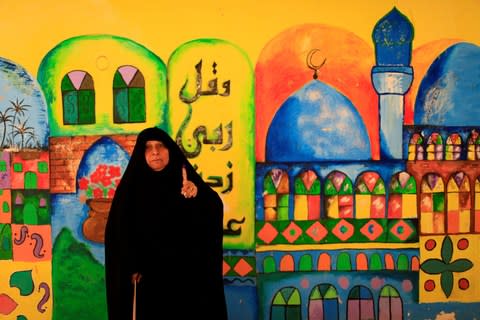 An Iraqi woman shows her ink-stained finger after casting her vote at a polling station during the parliamentary election in the Sadr city district of Baghdad - Credit: Reuters