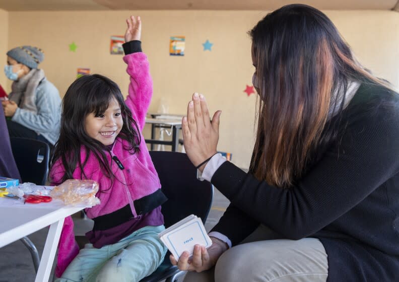 VAN NUYS, CA - NOVEMBER 09, 2020: Nikki Perez, project manager for Kids First celebrates with a 4 year old transitional kindergartner after she successfully learns to say different colors in English and Spanish at a learning pod for homeless children, located in the carport at the Hyland Motel in Van Nuys. (Mel Melcon / Los Angeles Times)