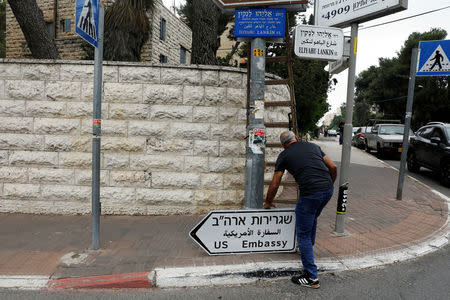 A worker holds a road sign directing to the U.S. embassy, in the area of the U.S. consulate in Jerusalem, May 7, 2018. REUTERS/Ronen Zvulun