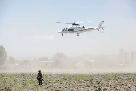 A soldier keeps watch near the site damaged due to fireworks explosions as a helicopter hovers in the municipality of Tultepec, on the outskirts of Mexico City, Mexico July 5, 2018. REUTERS/Daniel Becerril