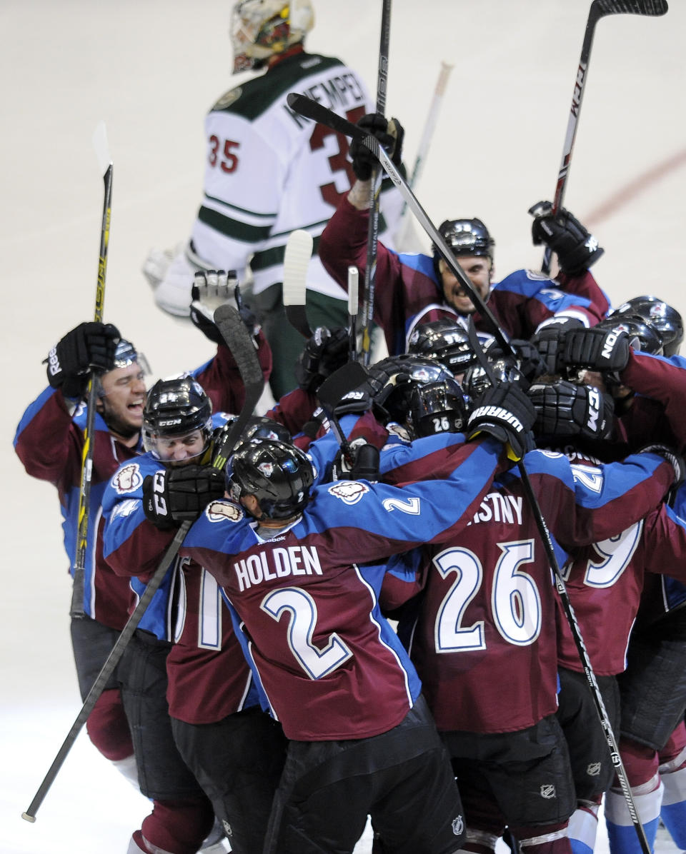 The Colorado Avalanche celebrate as Minnesota Wild goalie Darcy Kuemper skates past after a game-winning goal by Nathan MacKinnon in overtime in Game 5 of an NHL hockey first-round playoff series on Saturday, April 26, 2014, in Denver. The Avalanche won 4-3. (AP Photo/Chris Schneider)