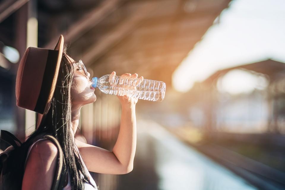 Woman Drinking Water From Bottle At Railroad Station Platform