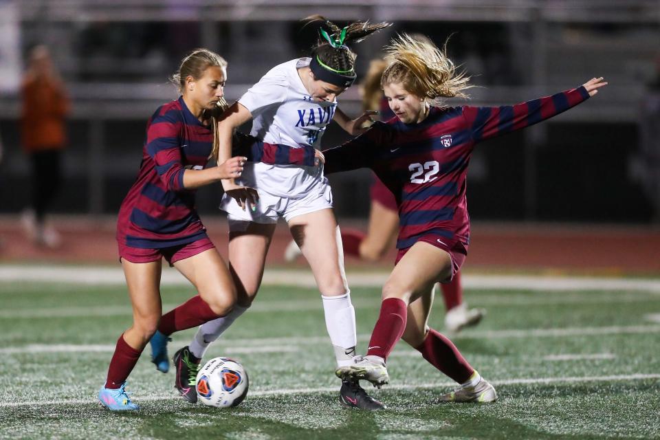 Bella Leonard (10), center, has the ball taken away from her by Perry's Julia Sauter, (18), left, during the second half of sudden death period of the 6A girls High School Soccer Championship between Perry High School and Xavier Xavier College Preparatory on Thursday, Feb. 24, 2022, in Gilbert.