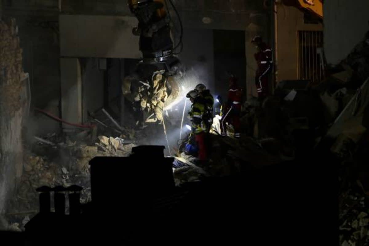 Emergency service personnel watch as an excavator moves rubble at ‘rue Tivoli’ after a building collapsed in the street, in Marseille, southern France, on 9 April 2023 (AFP via Getty Images)