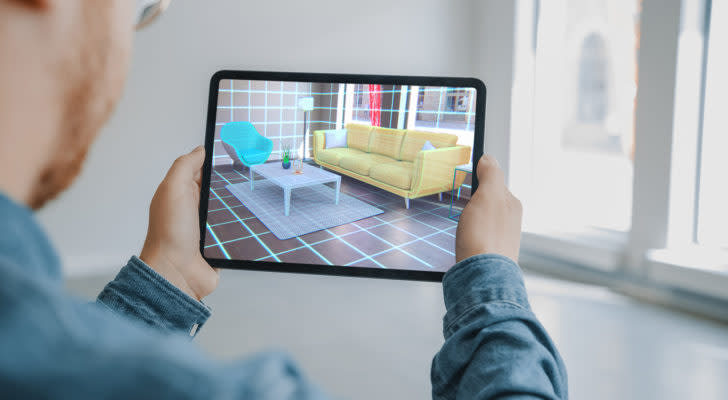 man holding digital tablet with AR interior design software chooses 3D furniture for home