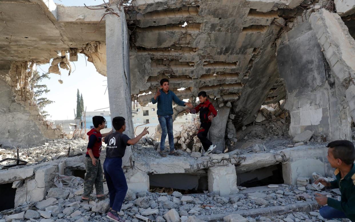 Children play at the ruins of a building destroyed in an air strike by coalition forces during fightings with Islamic State militants in Kobani - REUTERS