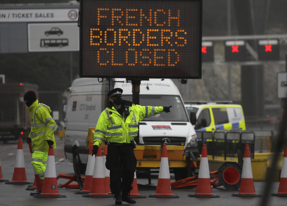 A police officer directs traffic at the entrance to the closed ferry terminal in Dover, England, Monday, Dec. 21, 2020, after the Port of Dover was closed and access to the Eurotunnel terminal suspended following the French government's announcement. France banned all travel from the UK for 48 hours from midnight Sunday, including trucks carrying freight through the tunnel under the English Channel or from the port of Dover on England's south coast. (AP Photo/Kirsty Wigglesworth)