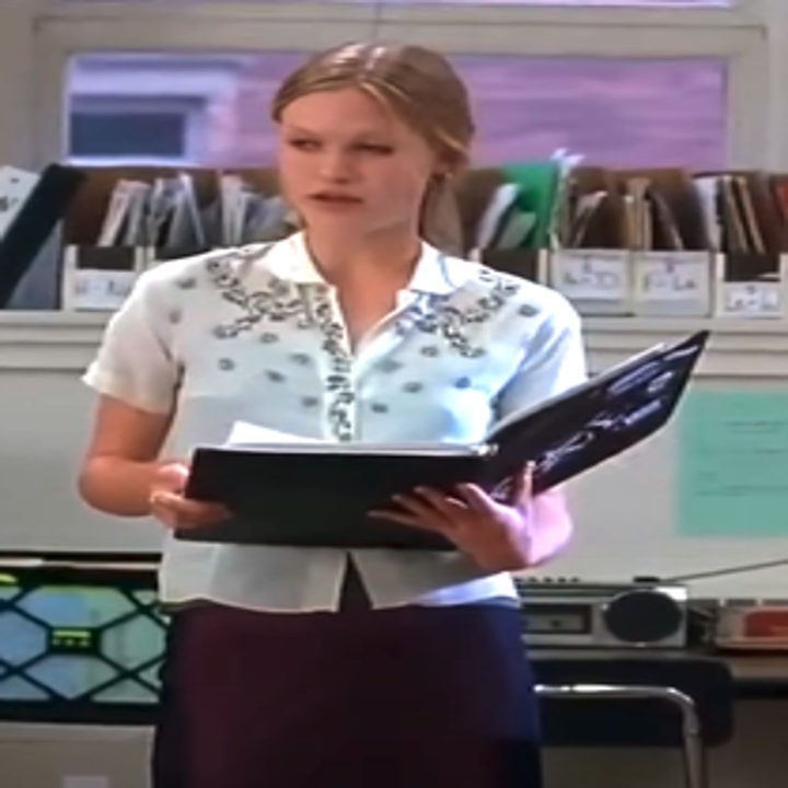 Julia in the movie standing in a classroom holding a loose-leaf notebook open