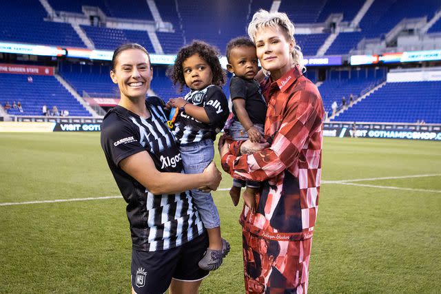 <p>Ira L. Black - Corbis/Getty</p> From Left: Ali Krieger, the couple's to kids and Ashlyn Harris in May 2023