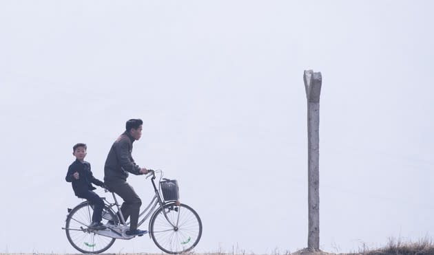 A man and boy ride a bicycle near Sinuiju, North Korea, across the border from Dandong, China, on April 15, 2017. See more photos from the North Korean border <a href="https://www.theatlantic.com/photo/2017/04/along-the-north-korean-border/523404/" rel="nofollow noopener" target="_blank" data-ylk="slk:here;elm:context_link;itc:0;sec:content-canvas" class="link ">here</a>. (Johannes Eisele / AFP / Getty)