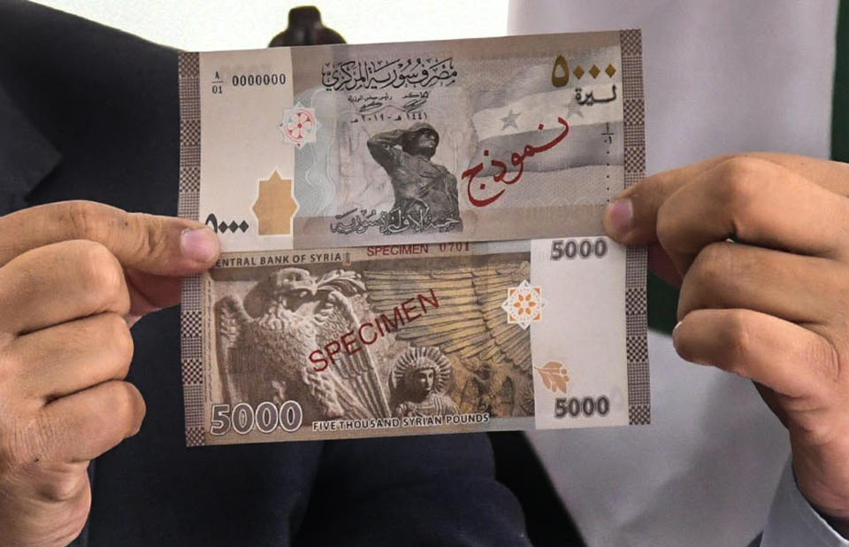 In this photo released by the Syrian official news agency SANA, Iyed Bilal, the director of the treasury department of the Syrian Central Bank, shows the new banknote of 5000 Syrian pounds during a press briefing, in Damascus, Syria, Sunday, Jan. 24, 2021. The new 5,000 Syrian Lira bank note goes into circulation Sunday, the largest denomination in the country reeling from 10 years of conflict and a crippling economic crisis. (SANA via AP)