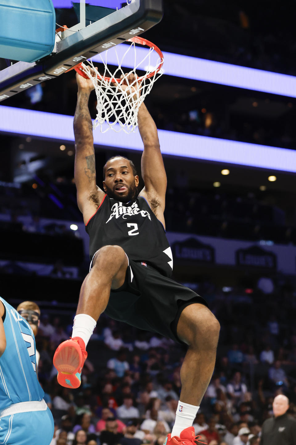 Los Angeles Clippers forward Kawhi Leonard hangs on the rim after dunking against the Charlotte Hornets in an NBA basketball game in Charlotte, N.C., Sunday, March 31, 2024. (AP Photo/Nell Redmond)