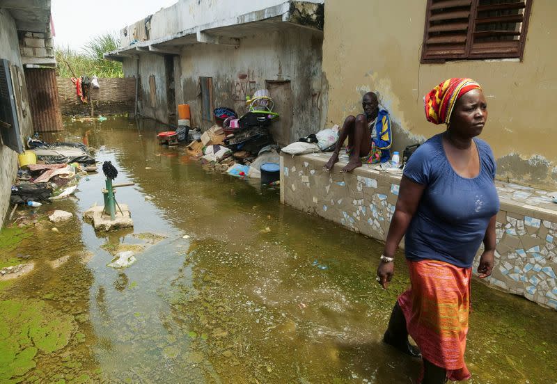 Mrs. Aicha Sy and Mr. Issa Camara, residents, are pictured in the flooded alley of their home after heavy rains in Yeumbeul district on the outskirts of Dakar