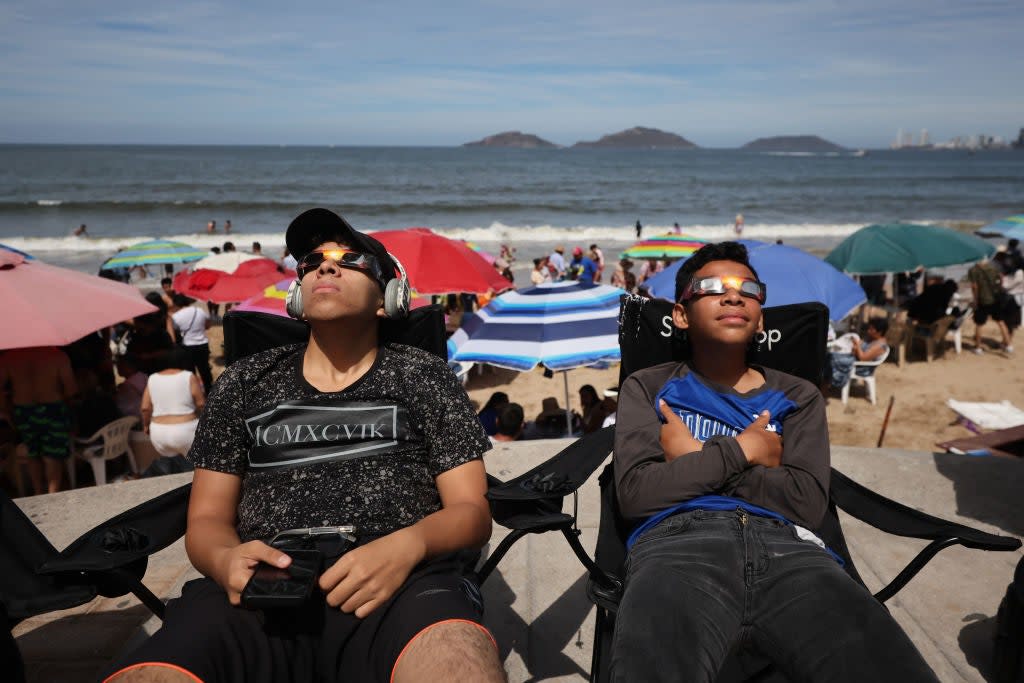 Kids use glasses to enjoy the eclipse from the beach on 8 April, 2024 in Mazatlan, Mexico (Getty Images)