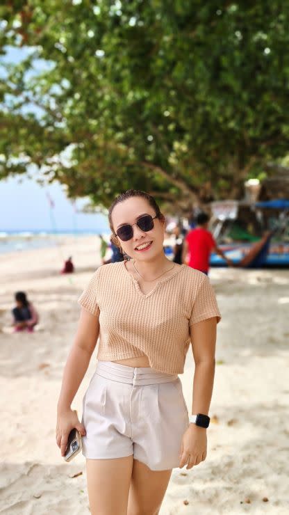 A woman in sunglasses and a tan top enjoying the beach