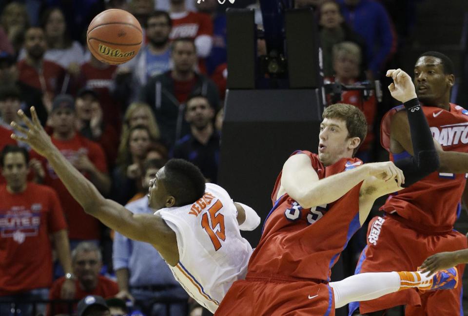 Florida forward Will Yeguete (15) falls to the court as Dayton forward/center Matt Kavanaugh (35) defends during the second half in a regional final game at the NCAA college basketball tournament, Saturday, March 29, 2014, in Memphis, Tenn. (AP Photo/Mark Humphrey)