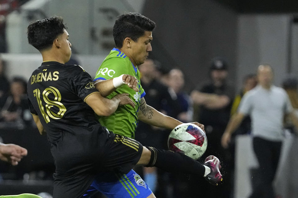 Los Angeles FC defender Erik Duenas, left, kicks the ball as it bounces in front of Seattle Sounders forward Fredy Montero during the first half of a Major League Soccer match Wednesday, June 21, 2023, in Los Angeles. (AP Photo/Mark J. Terrill)