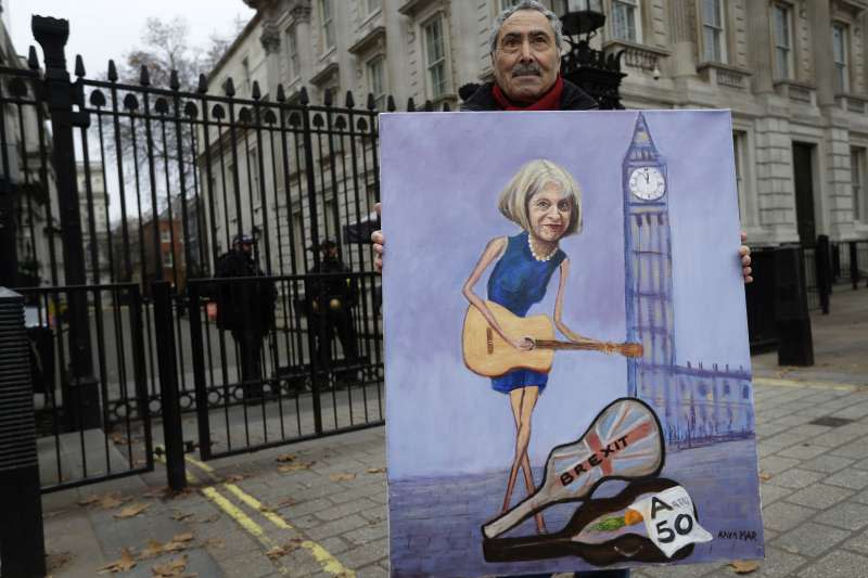 一名英國畫家拿著梅伊的畫像在英國國會前。(AP)