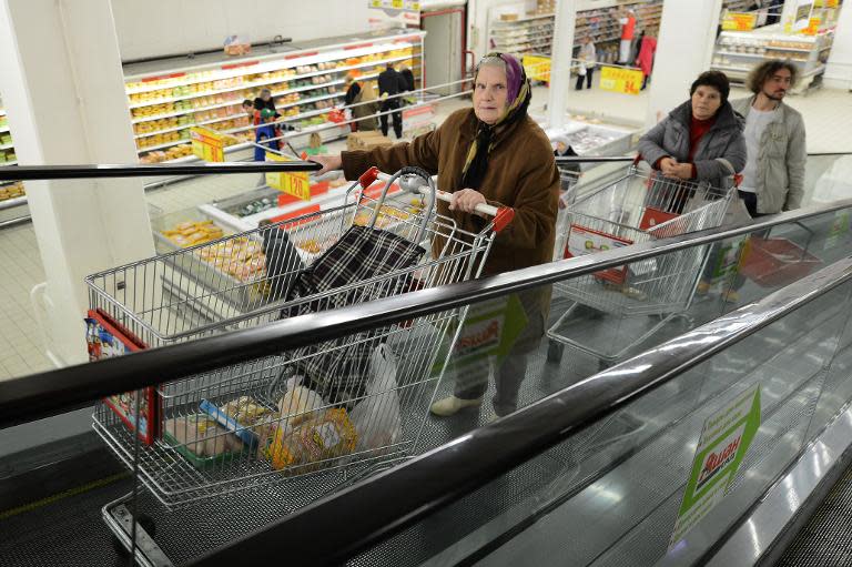 Customers hold their shopping carts as they ride the travalator in an Auchan Hypermarket in Moscow, on October 22, 2012