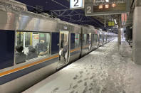 A train stops due to a power outage at Nishioji Station in Kyoto, western Japan Wednesday, Jan. 25, 2023. Snow and cold weather were affecting much of Japan on Wednesday, disrupting highway, air and train travel, and more snow and cold temperatures were forecast. (Kyodo News via AP)