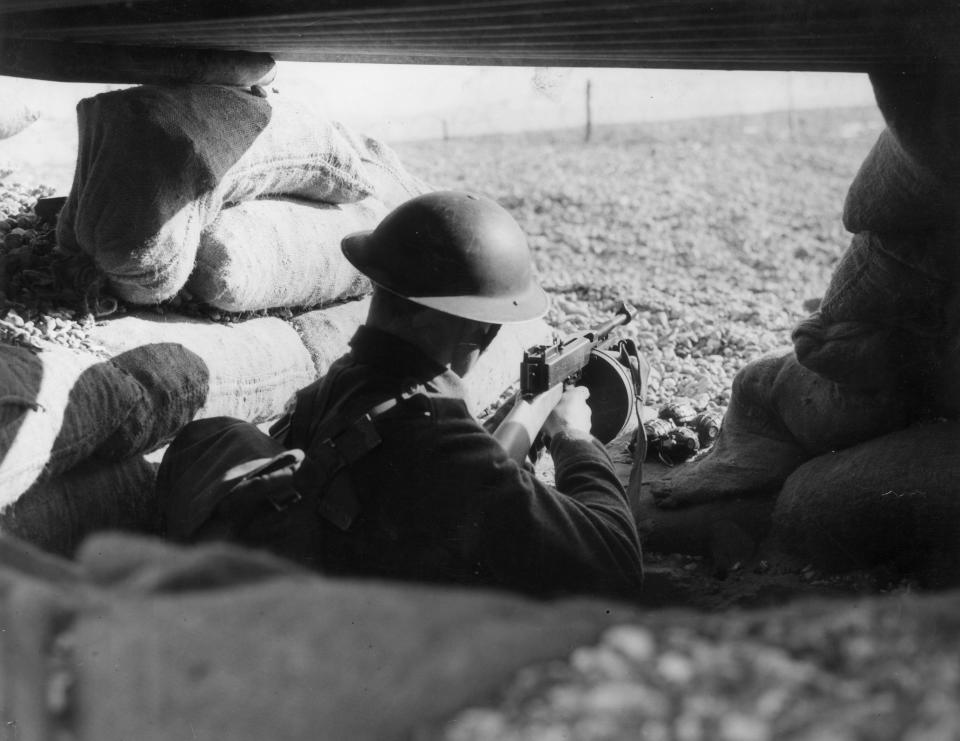 A soldier in a sandbagged trench on a beach on the English coast, circa 1940.