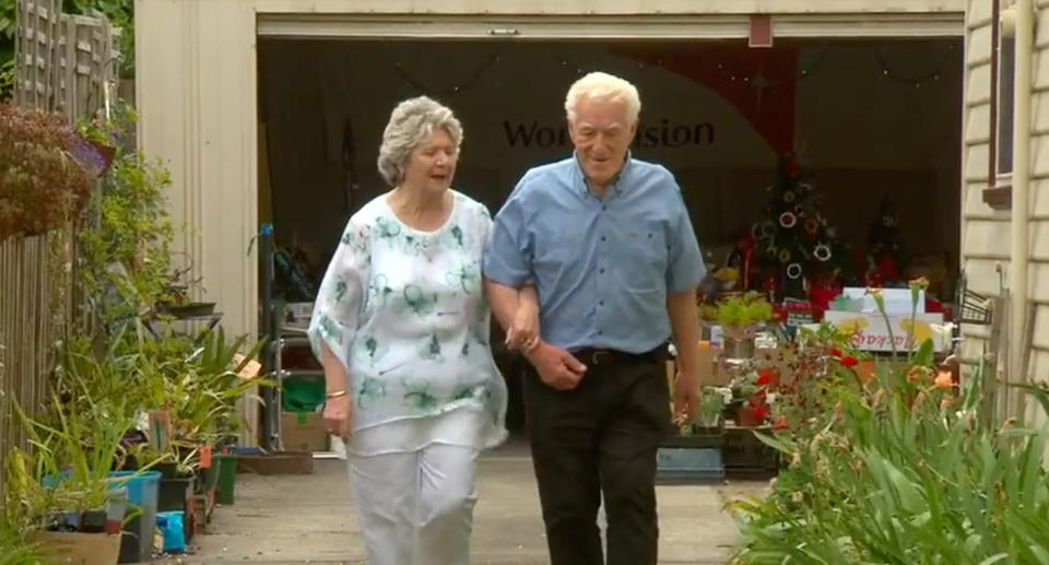 Maureen and Ron walking in front of their garage sale. 