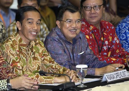 Indonesian presidential candidate Joko "Jokowi" Widodo (L) and his running mate Jusuf Kalla smile as they sit inside the Elections Commission headquarters in central Jakarta July 22, 2014. Jokowi was declared the winner of Indonesia's presidential election on Tuesday, bringing the promise of major reforms to the world's third largest democracy. REUTERS/Darren Whiteside