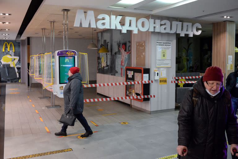 En esta foto de archivo tomada el 16 de marzo de 2022, la gente camina junto a un restaurante McDonald's cerrado en un centro comercial en Moscú. El gigante estadounidense de comida rápida McDonald's, que cerró sus tiendas en Rusia a principios de marzo, anunció el 16 de mayo de 2022 que se retiraría del país y vendería todas sus operaciones en respuesta a la invasión rusa de Ucrania