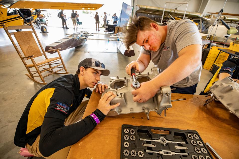 Caleb Brock, left, and Weston Dudley from McKinnet, Texas, work on an aircraft engine in the Lakeland Aero Club hangar at the Sun 'n Fun Aerospace Expo in 2023.