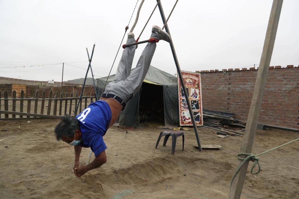 Circus clown Santos Chiroque, whose performance name is "Piojito," or Little Tick, trains on a self-made swing outside his home on the outskirts of Lima, Peru, Monday, Aug. 10, 2020. Chiroque's family used to run their own small circus, but since March when the lockdown to curb COVID-19 closed their business, and the requirement for people over 60 to self-quarantine kept the 74-year-old at home, they started selling circus food like caramelized apples to survive. (AP Photo/Martin Mejia)