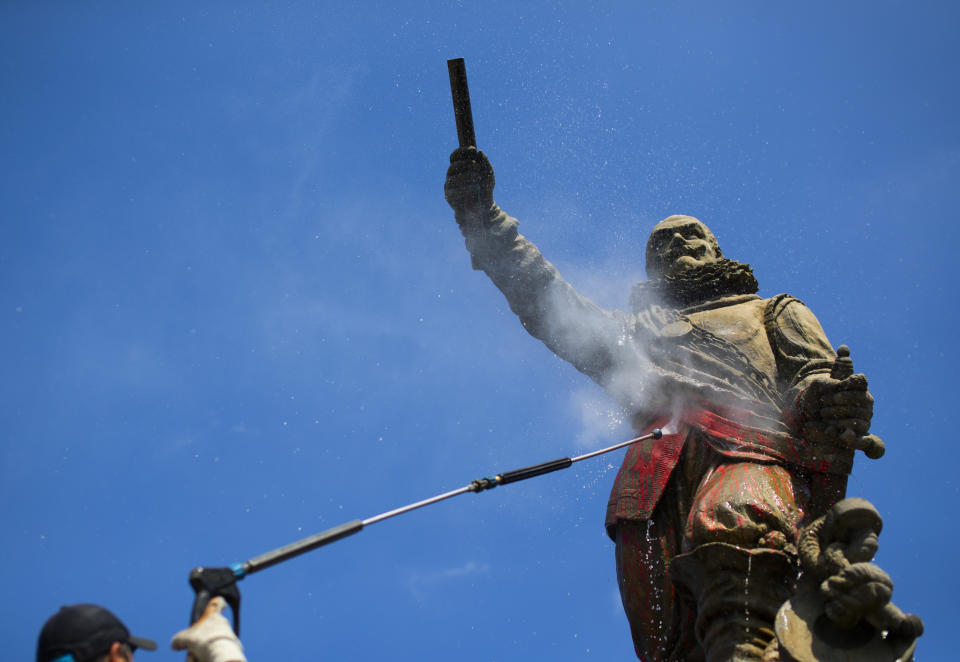 In this Friday June 12, 2020, file image, A municipal worker uses a high pressure water cleaner to remove the paint from the statue of Piet Hein in Rotterdam, Netherlands, Friday, June 12, 2020. Dutch activists have spray painted the words "killer" and "thief" and daubed red paint on a statue of a man regarded by many as a naval hero from the 17th-century Golden Era of Dutch trade and colonial expansion. (AP Photo/Peter Dejong, File)