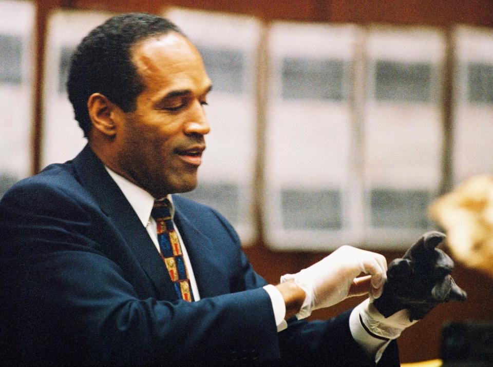 PHOTO: O.J. Simpson tries on a leather glove allegedly used in the murders of Nicole Brown Simpson and Ronald Goldman during testimony in Simpson's murder trial June 15, 1995 in Los Angeles. (Lee Celano/WireImage via Getty Images, FILE)