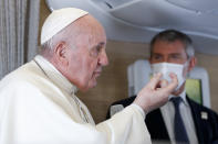 Pope Francis speaks to journalists, Monday, March 8, 2021, while flying back to The Vatican at the end of his four-day trip to Iraq where he met with different Christian communities and Shiite revered cleric Grand Ayatollah Ali al-Sistani. At right pope's spokesperson Matteo Bruni. (AP Photo/Yara Nardi, pool)