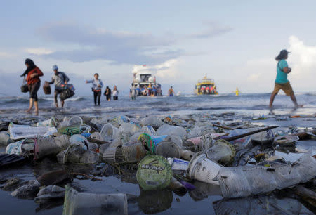 FILE PHOTO: Tourists and local residents disembark a boat coming from nearby Nusa Penida island as plastic trash pollutes the beach in Sanur, Denpasar, Bali, Indonesia April 10, 2018. REUTERS/Johannes P. Christo/File Photo