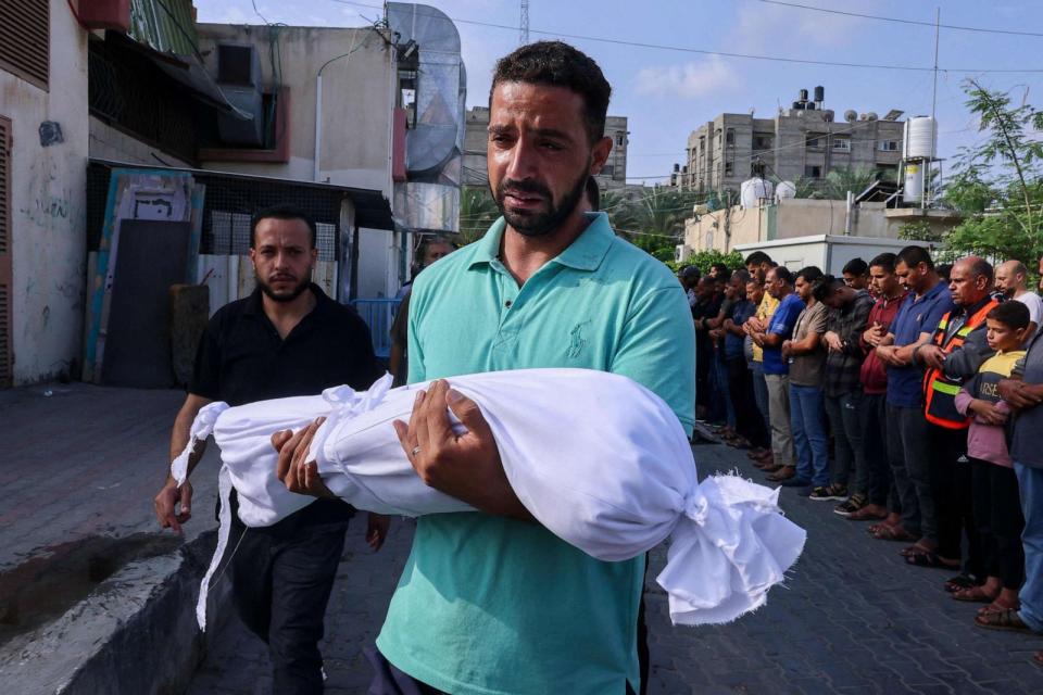 PHOTO: A Palestinian man carries the body of a child killed in overnight Israeli shelling during a funeral in Khan Yunis in the southern Gaza Strip, on Oct. 10, 2023. (Said Khatib/AFP via Getty Images)