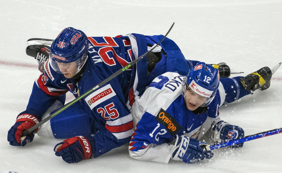 United States' Tyler Kleven (25) looks toward the puck after checking Slovakia's Samuel Knazko (12) to the ice during first period IIHF World Junior Hockey Championship action in Red Deer, Alberta, on Sunday, Dec. 26, 2021. (Jonathan Hayward/The Canadian Press via AP)