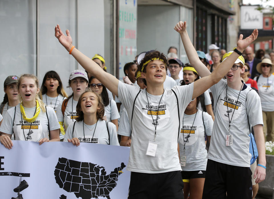 Jack Torres, 16, a Somerville, Mass., high school student, center, raises his arms while walking in a planned 50-mile march, Thursday, Aug. 23, 2018, in Worcester, Mass. The march, held to call for gun law reforms, began Thursday, in Worcester, and is scheduled to end Sunday, Aug. 26, in Springfield, Mass., at the headquarters of gun manufacturer Smith & Wesson. (AP Photo/Steven Senne)