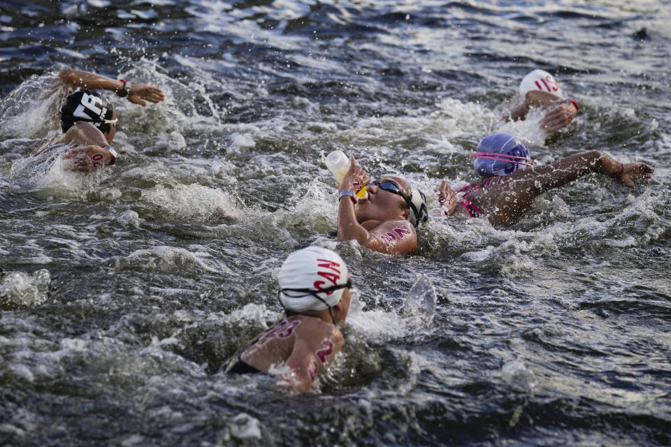 Samantha Arevalo, center, of Ecuador, takes a drink at a feeding station during the women's marathon swimming event at the 2020 Summer Olympics, Wednesday, Aug. 4, 2021, in Tokyo, Japan. (AP Photo/Jae C. Hong)